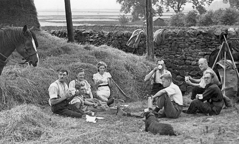 Harvest lunch at Thwaites Farm 1941.JPG - Lunch break from hay making at the dutch barn in the Sourdie Lane Fields, Thwaites farm,  near the Consience House  - ( note that the Ings in the background is in flood).   One copy of this is dated 1940, another 1957.   Group on left: SimonThwaite, Harry Butterworth,  Agnes Thwaite, Richard Thwaite in front.  Group on Right: John (Jack) Nixon, Tommy Rose and in front Mr J.C. Sander ( Pastor at Methodist Church) & Joe Parker 